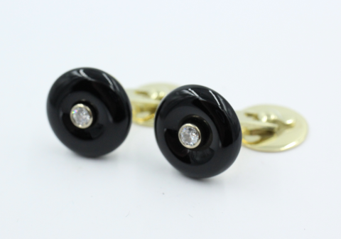 14 kt geelgouden manchetknopen, vervaardigd uit een ronde donut vormige Onyx van 15 mm. Centraal een briljant van 0.08 ct . De knopen zijn vervaardigd in eigen atelier en is een uniek paar. Bruto gewicht 10.47 gram 